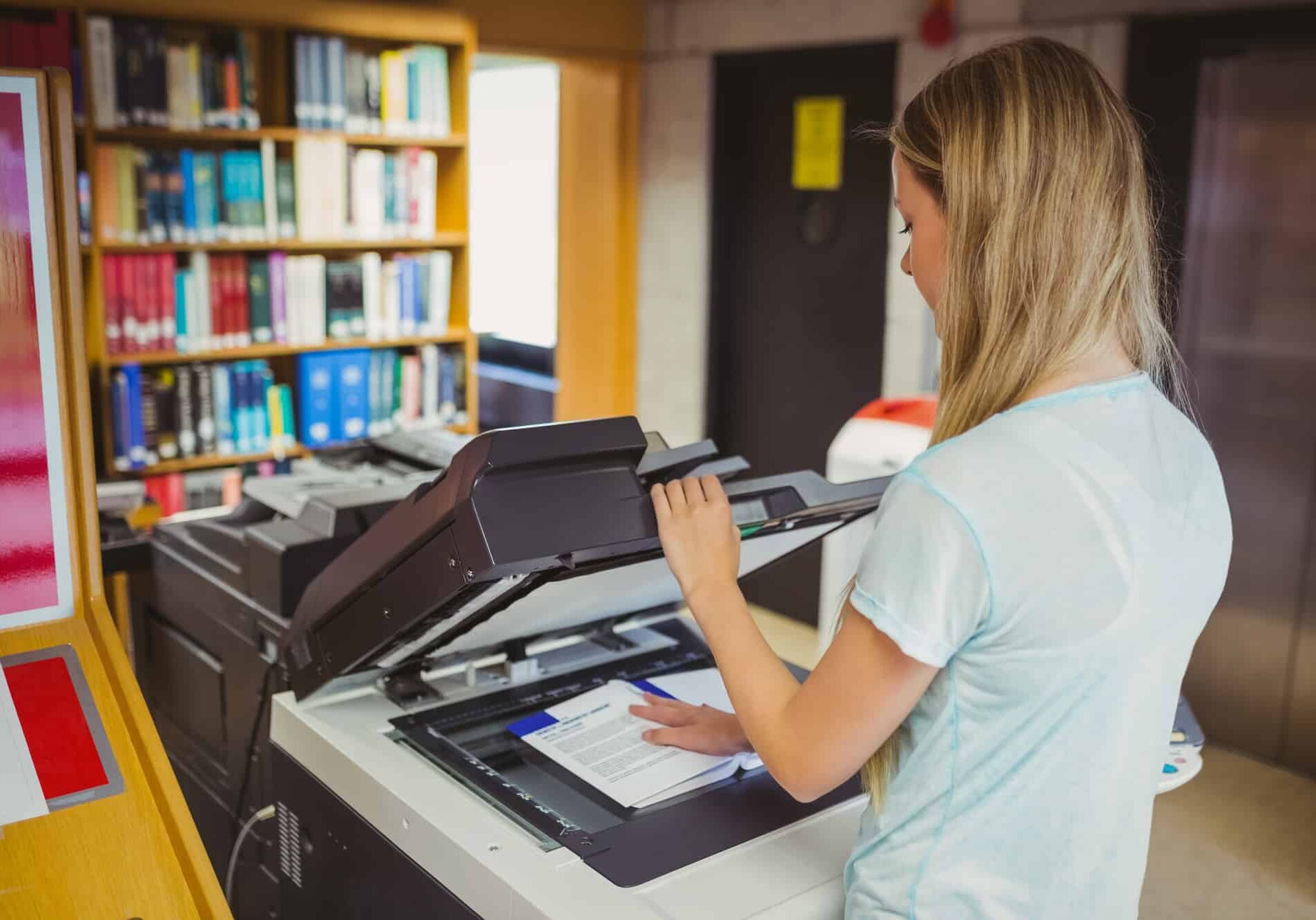 Smiling blonde student making a copy in library